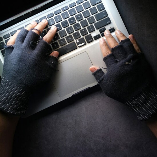Hände in fingerlosen Handschuhen an einem Laptop