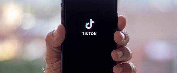 Hand hält Handy mit TikTok-Logo