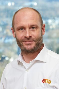 Ein professionell gekleideter Mann lächelt freundlich.