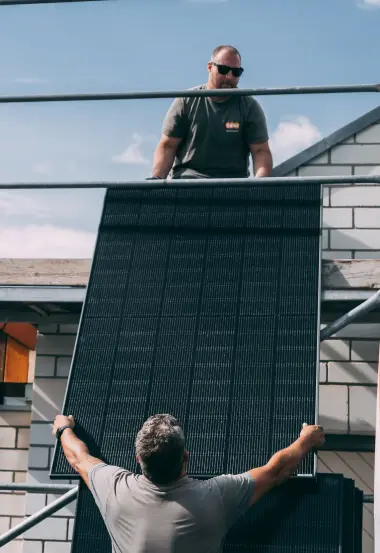 Handwerker reichen Solarpanel aufs Dach
