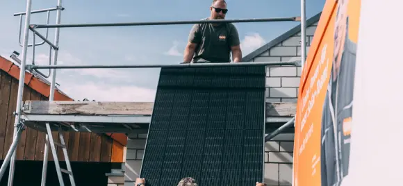 Handwerker reichen Solarpanel aufs Dach