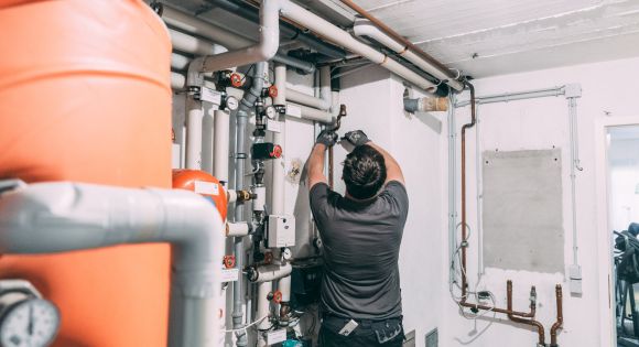 Ein evm Handwerker steht in einem Keller und arbeitet an einem Rohr.