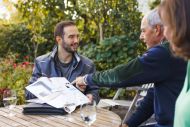Beratung Familie Elsenberger Solar evm Im Garten sitzen drei Personen um einen Tisch im Verkaufsgesräch