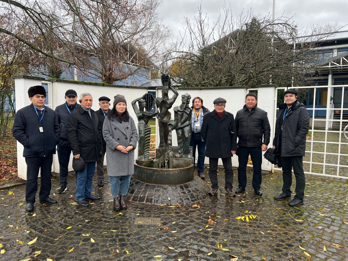 IMG_1917 Mehrere winterlich gekleidete Menschen stehen neben einer Skulptur vor dem Eingang eines Wasserwerks.