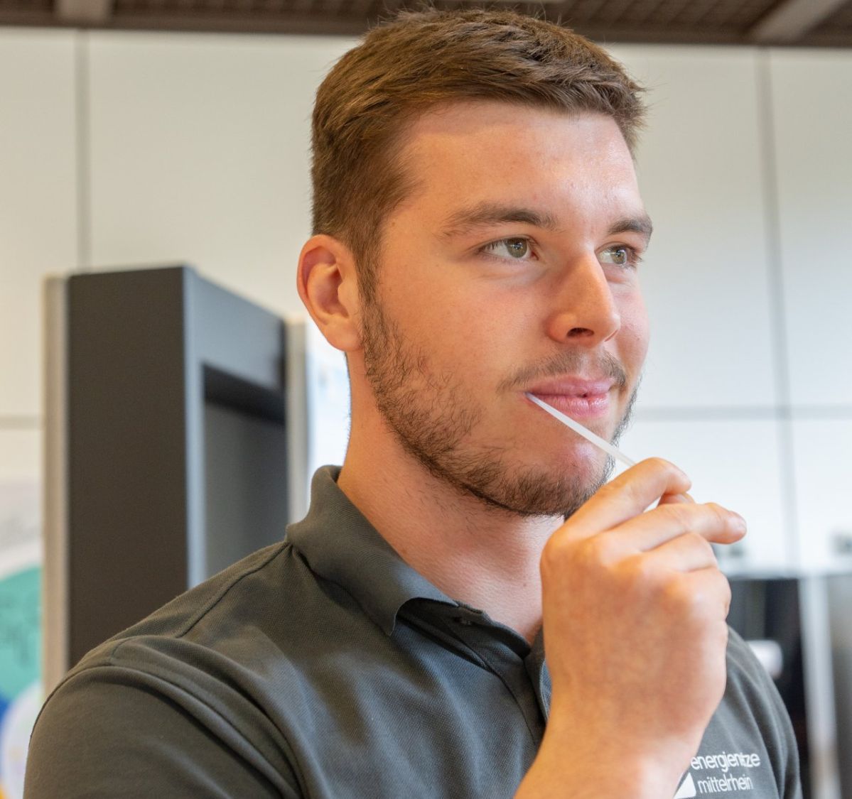 Ein Mann mit einem grauen enm Poloshirt hat ein schmales weißes Stäbchen im Mund.