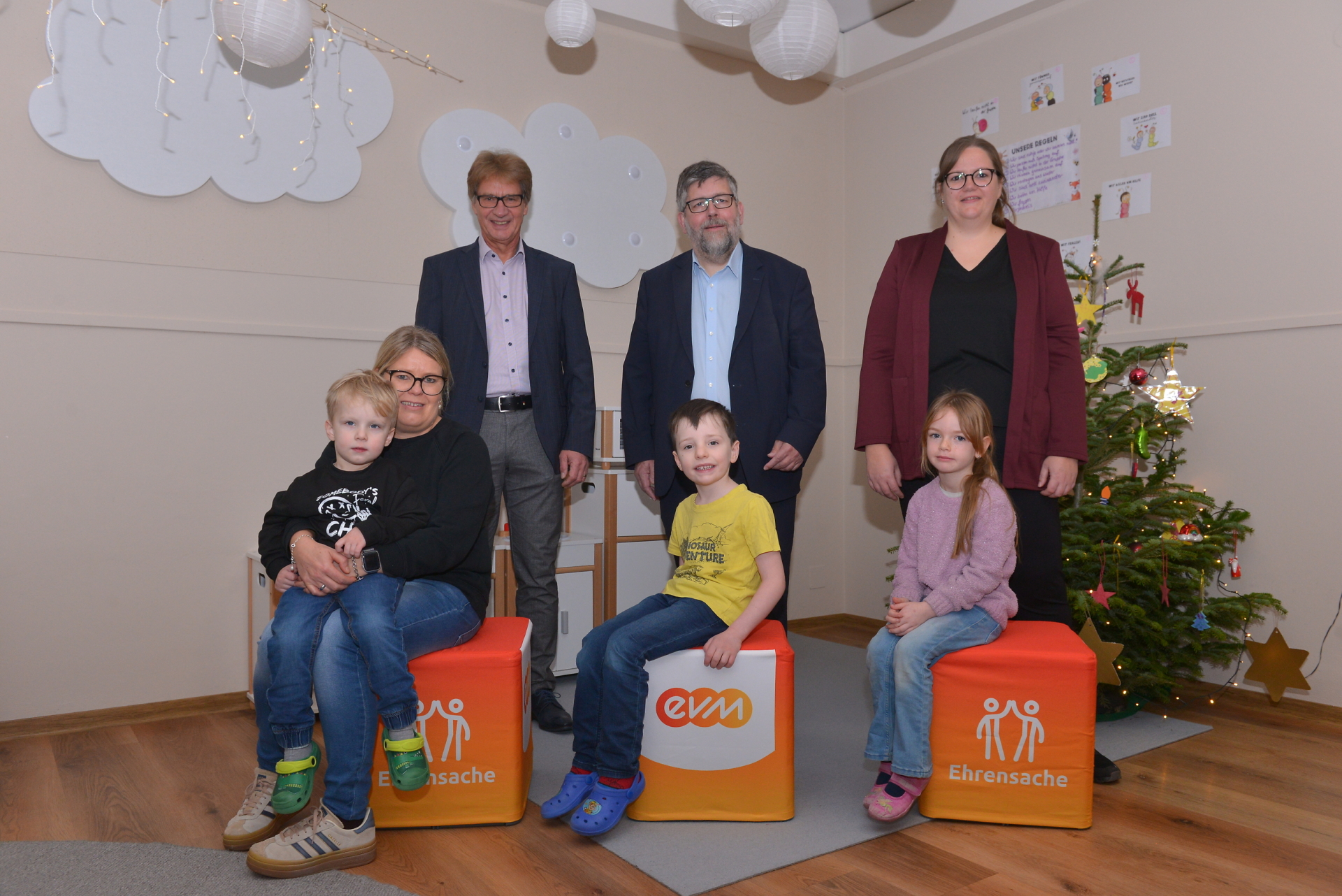 Erwachsene und Kinder posieren im Kindergarten Lieg für ein Gruppenfoto zur Übergabe einer 2.000‑Euro-Spende im Rahmen der evm Ehrensache.
