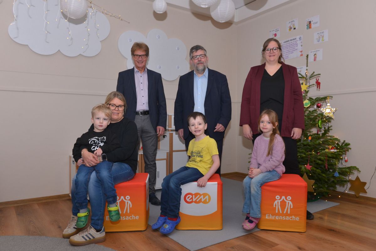 Erwachsene und Kinder posieren im Kindergarten Lieg für ein Gruppenfoto zur Übergabe einer 2.000‑Euro-Spende im Rahmen der evm Ehrensache.