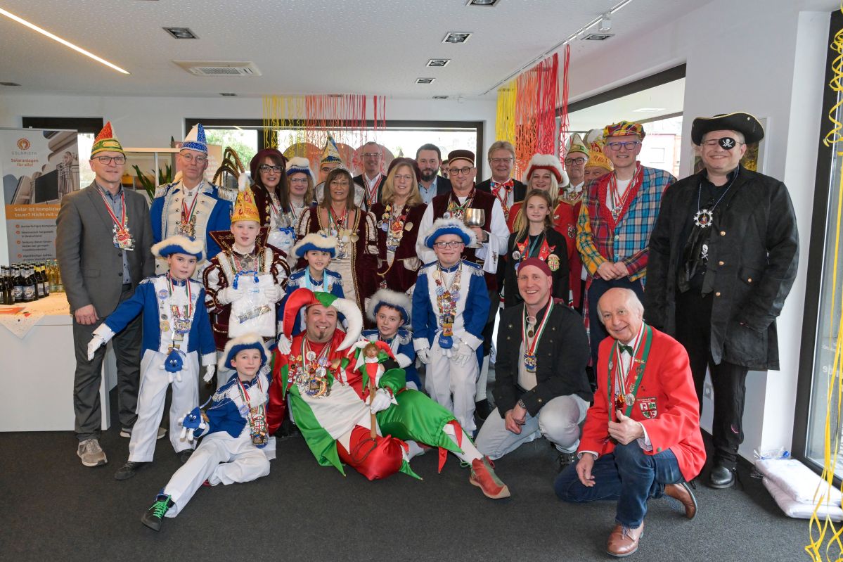 Eine große Gruppe von Karnevalisten steht in einem Raum und lächelt freundlich.