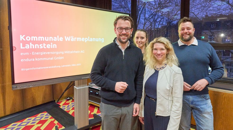 2 Männer und 2 Frauen stehen vor einem Bildschirm und lächeln freundlich in die Kamera. Auf dem Bildschirm steht " Kommunale Wärmeplanung Lahnstein - evm - Energieversorgung Mittelrhein AG endura kommunal GmbH Bürgerinformationsveranstaltung, Lahnstein, März 2025