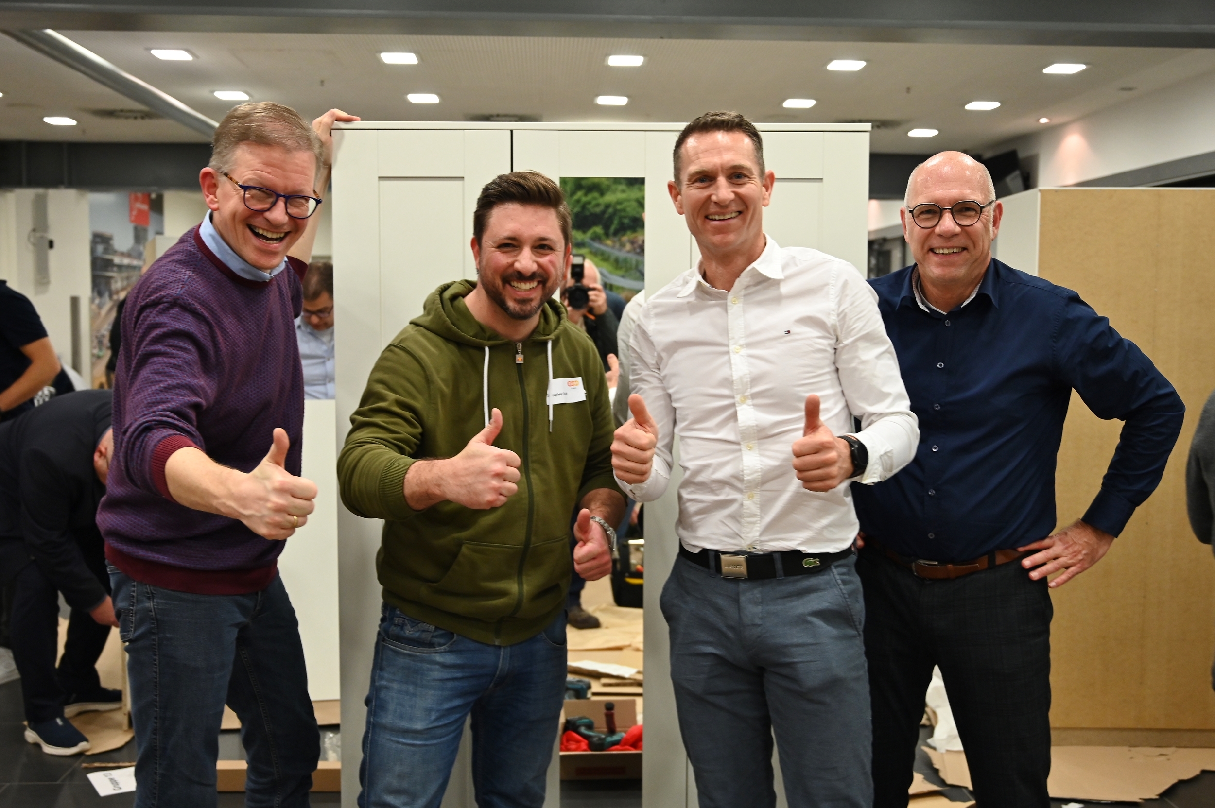 Vier Männer lächeln fröhlich in die Kamera und zeigen den Daumen hoch.