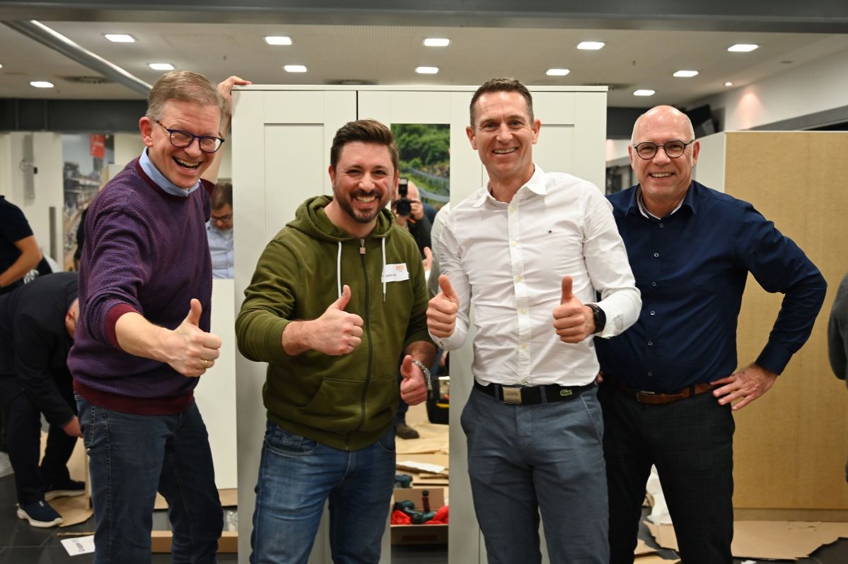 Vier Männer lächeln fröhlich in die Kamera und zeigen den Daumen hoch.