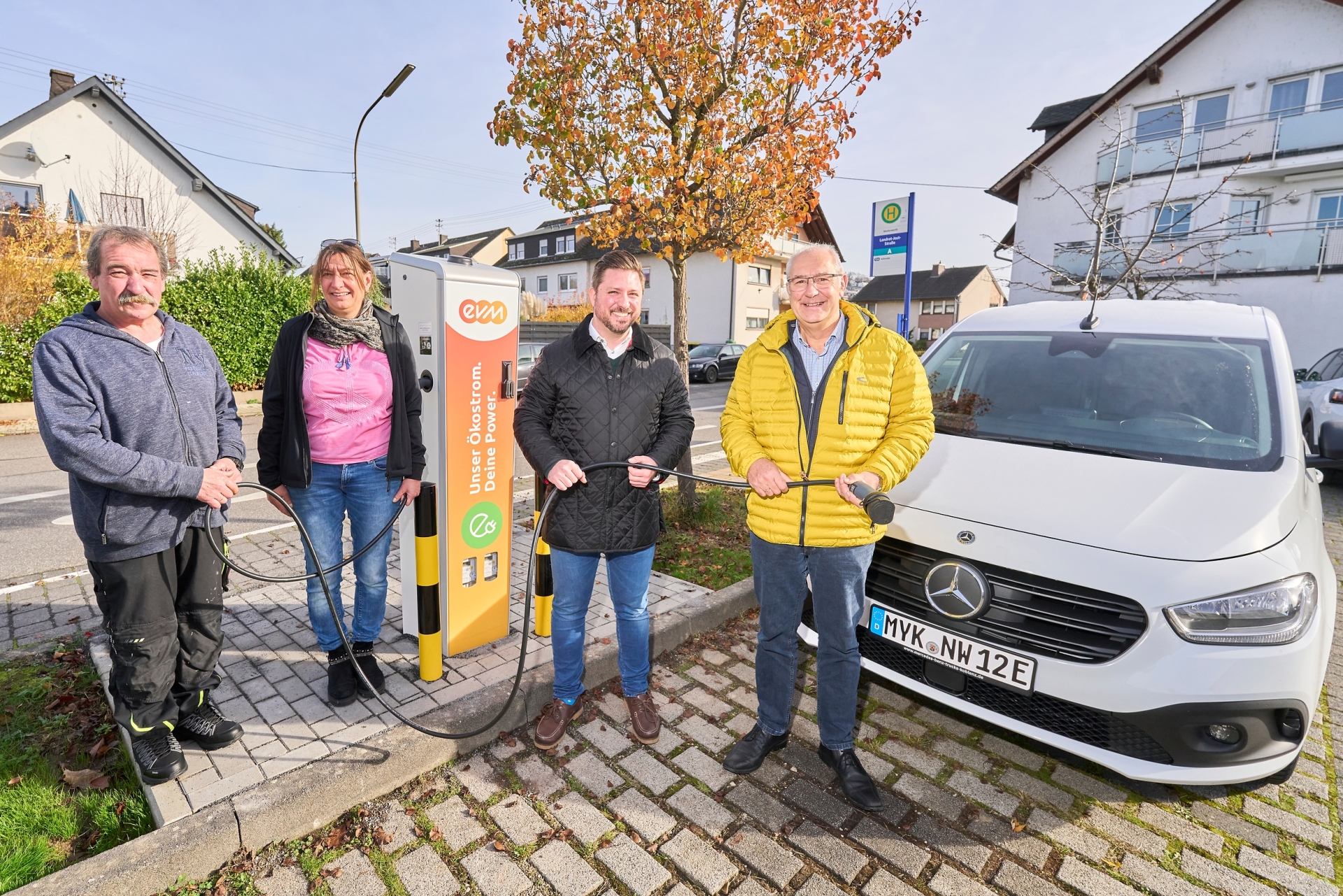 Vier Personen stehen um die Ladesäule der evm auf dem Niederwerth bei der Eröffnung