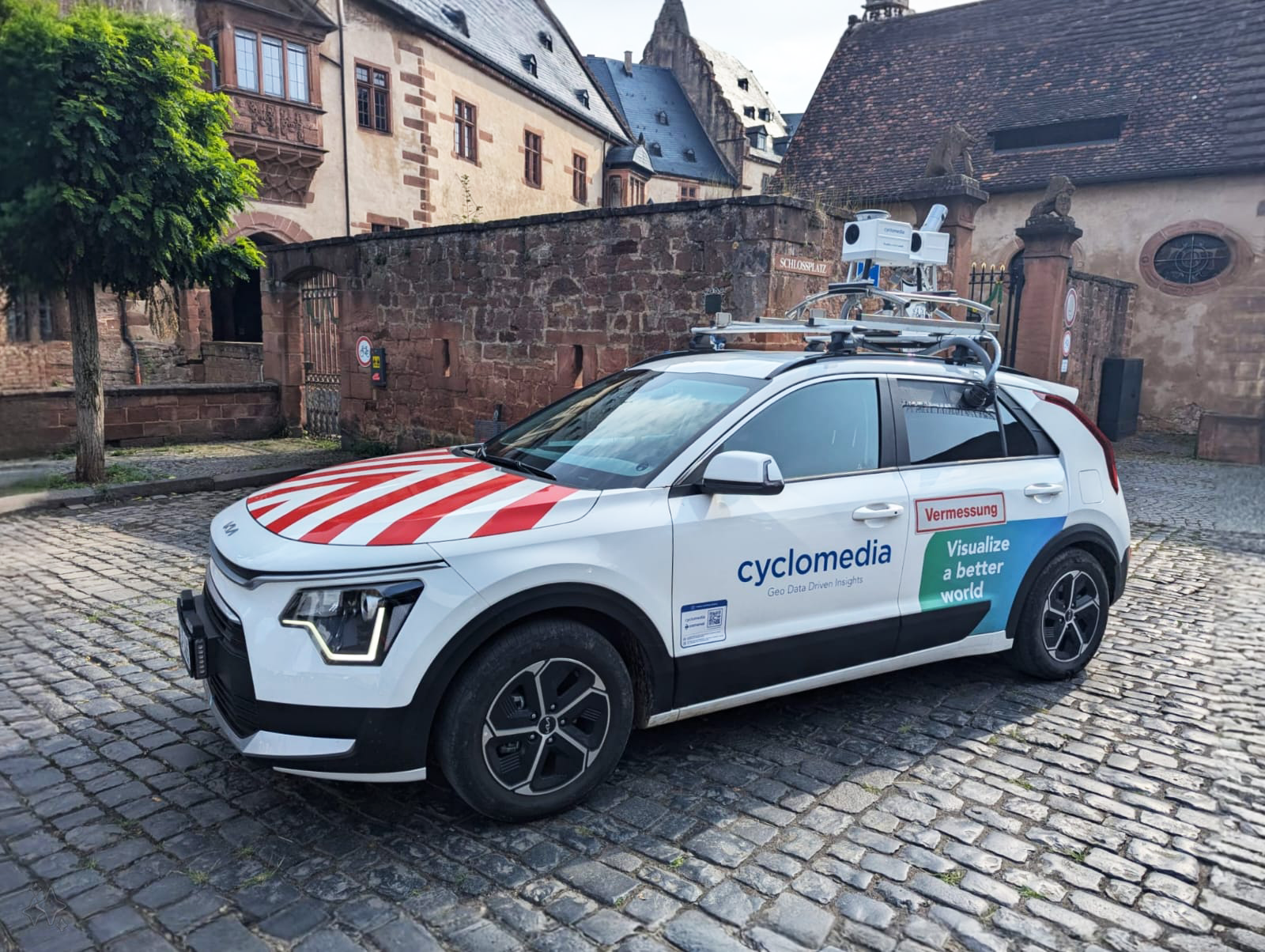 Ein Auto das mit einer Kamera ausgestattet ist, steht auf einem Platz. Aufschrift auf dem Auto "cyclomedia".