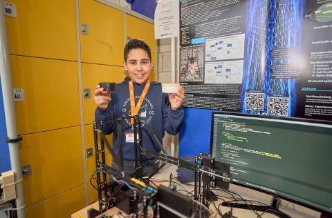 Matti Schönerstedt vom Bischöflichen Cusanus‑Gymnasium Boppard präsentiert beim Landeswettbewerb „Jugend forscht junior“ seinen selbst entwickelten 3D‑Scanner an einem Projekttisch.