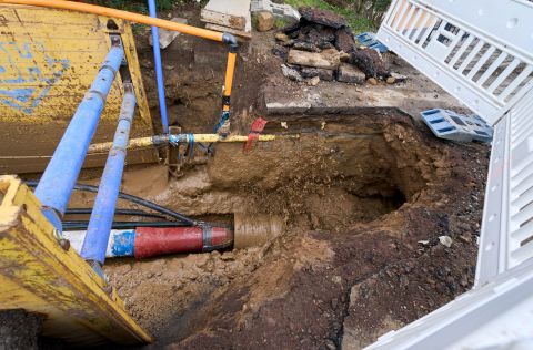 Blick in eine Baugrube mit freigelegten Leitungen und Erdreich, aufgenommen während des Einziehens der neuen Wassertransportleitung.