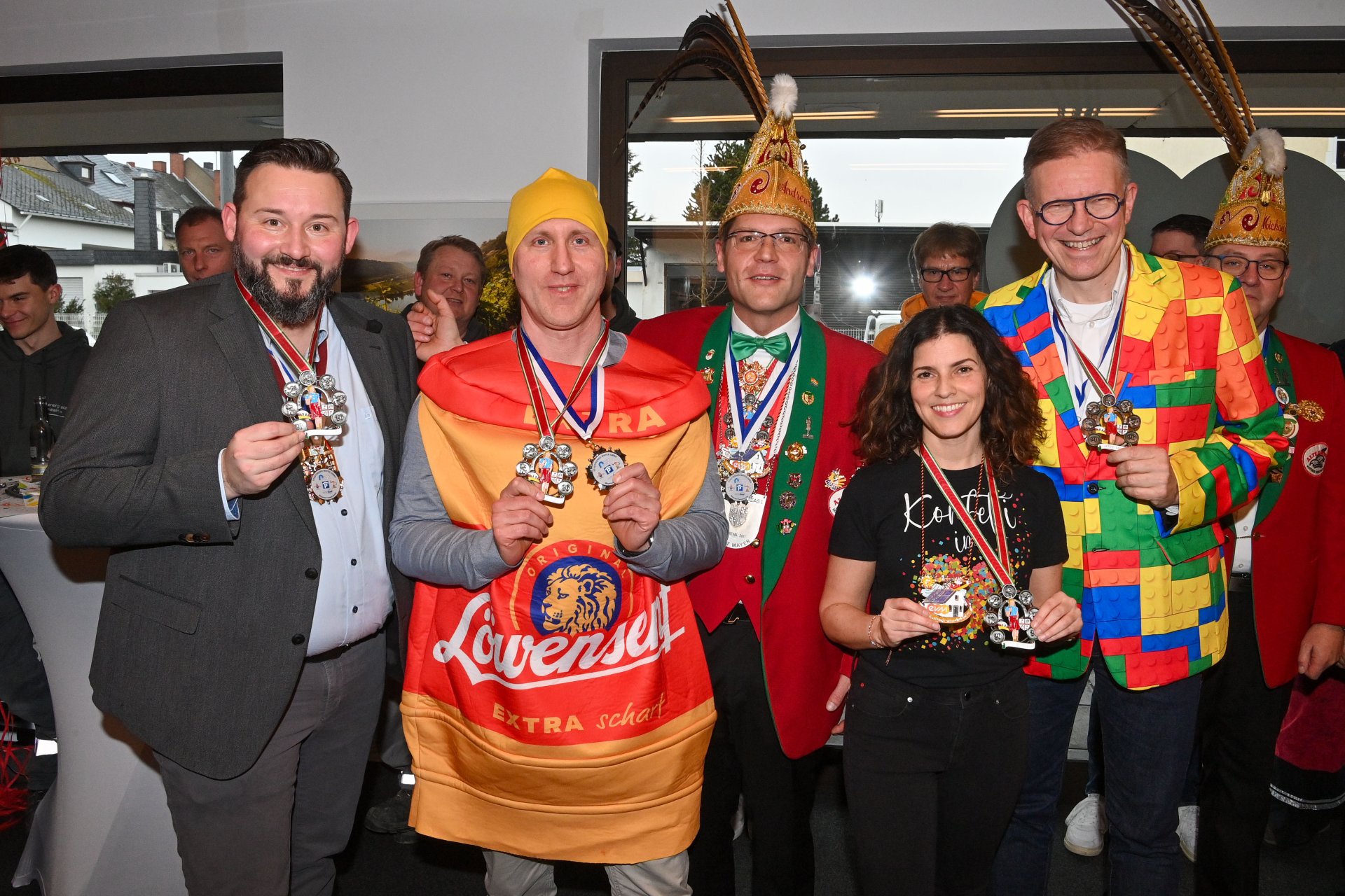 Karnevalsempfang Mayen Gruppe von Vertreterinnen und Vertretern der Stadtwerke Mayen, der evm‑Gruppe und der Alten Grossen Mayener Karnevalsgesellschaft beim Karnevalsempfang im Kundenzentrum, in farbenfrohen Kostümen und mit verliehenen Karnevalsorden.