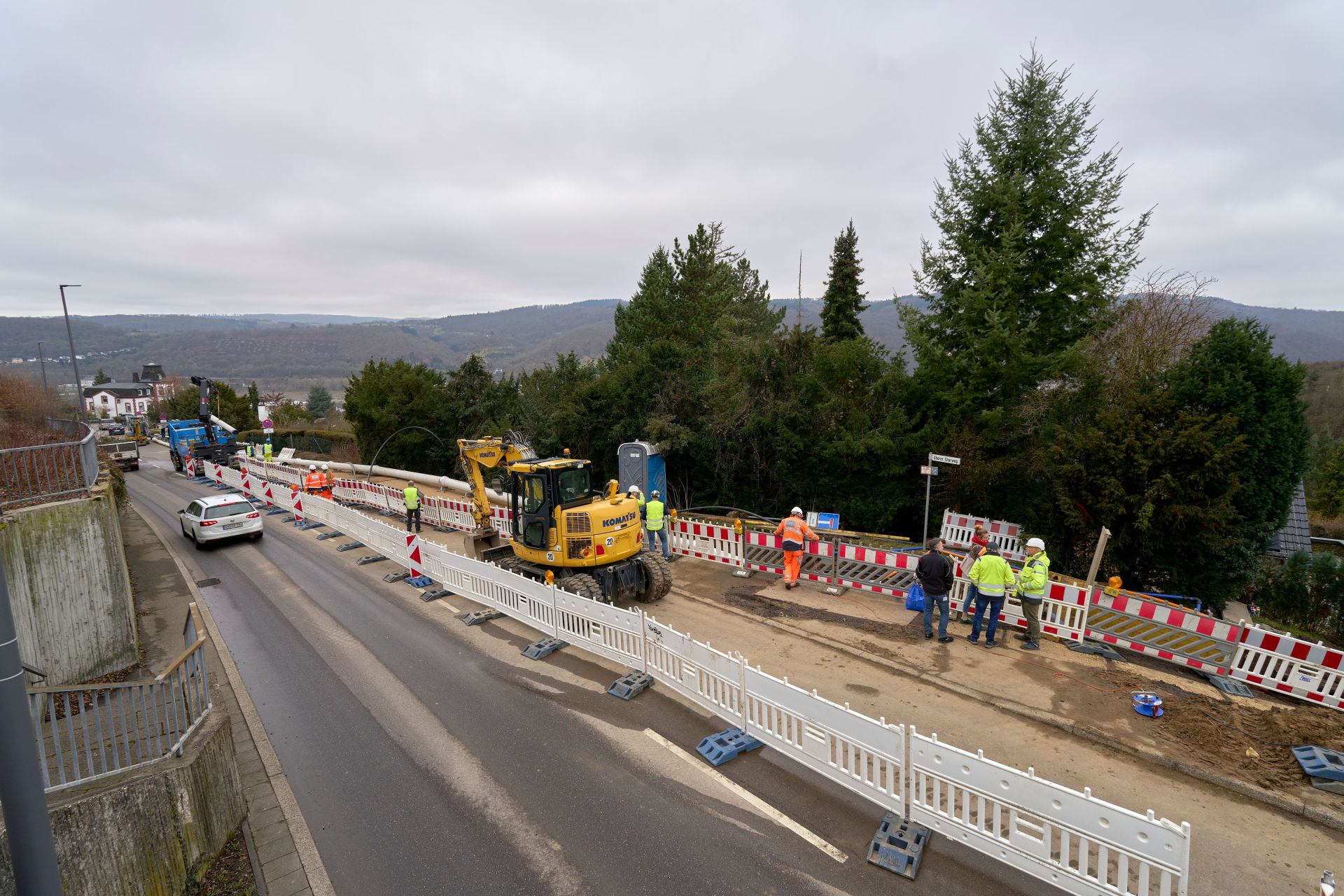 Baustelle am Oberen Charweg mit abgesicherter Arbeitszone, Baumaschinen und Baustellenpersonal entlang der Leitungsverlegung.