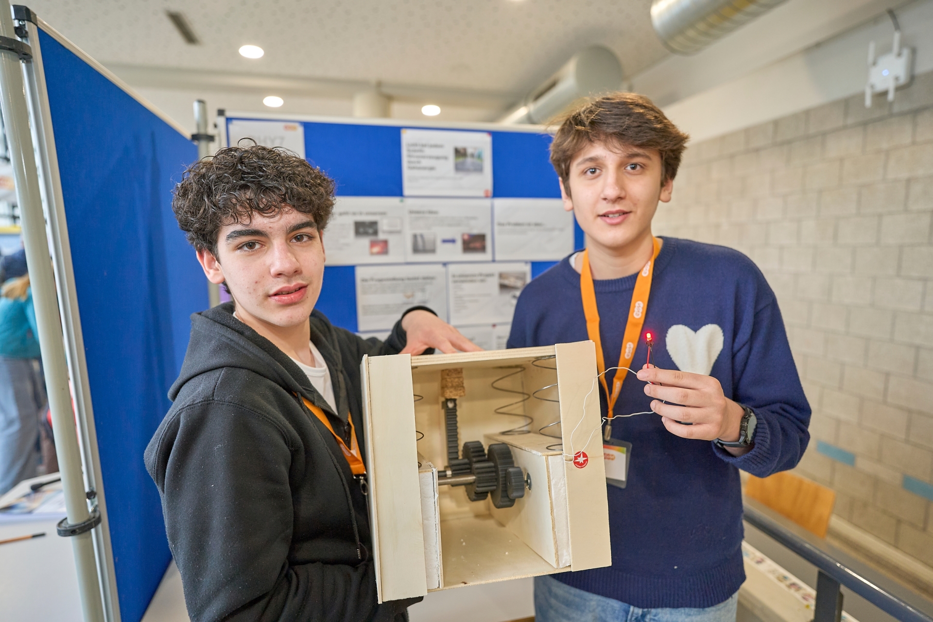 Zwei Teilnehmende präsentieren ein Modell einer stromerzeugenden Druckplatte an ihrem „Jugend forscht“-Stand.