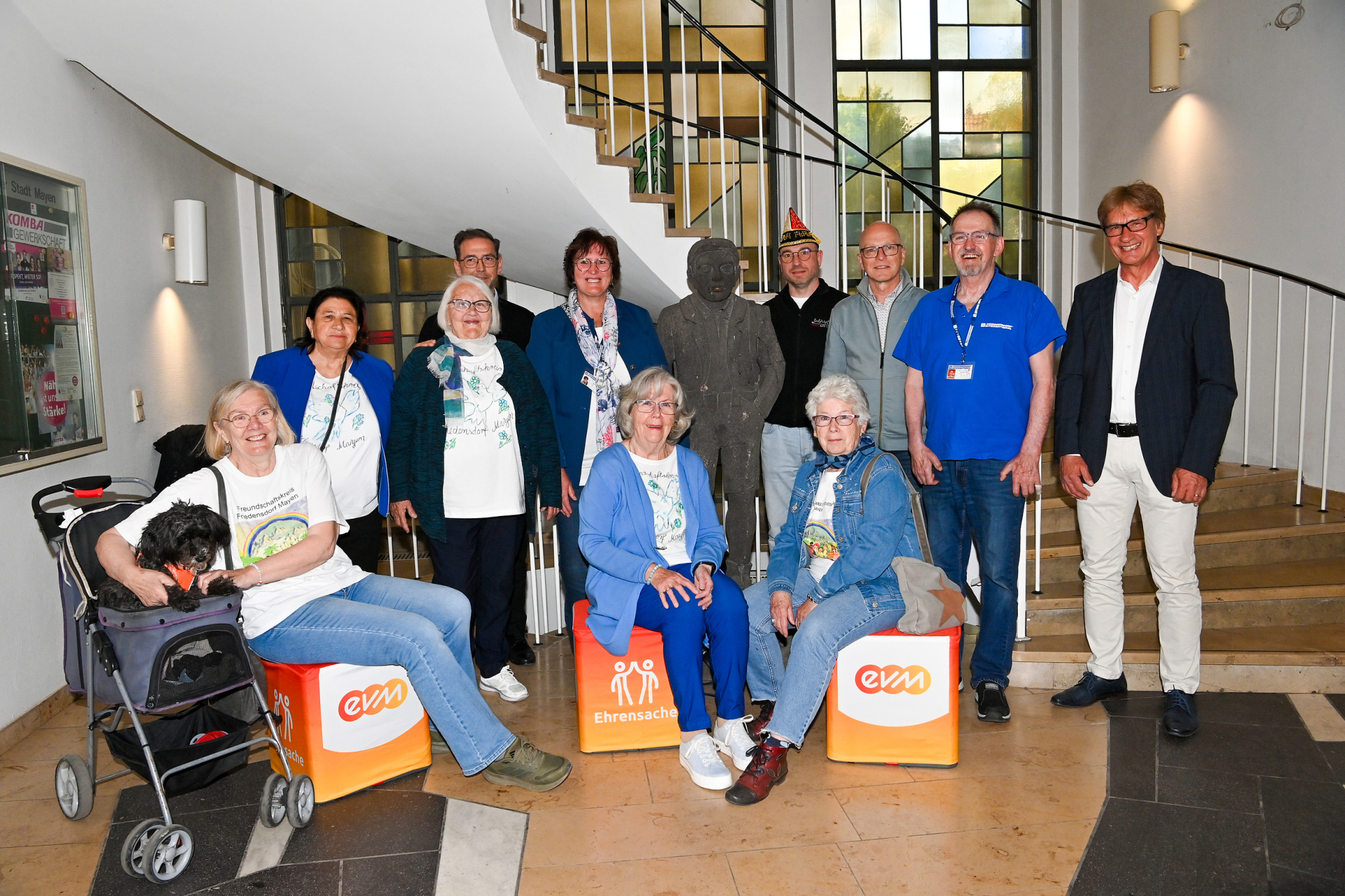Berthold Nick von der evm und Oberbürgermeister Dirk Meid stehen im Rathaus Mayen mit Vertreterinnen und Vertretern mehrerer Vereine bei der Übergabe von „evm‑Ehrensache“-Spendenboxen.