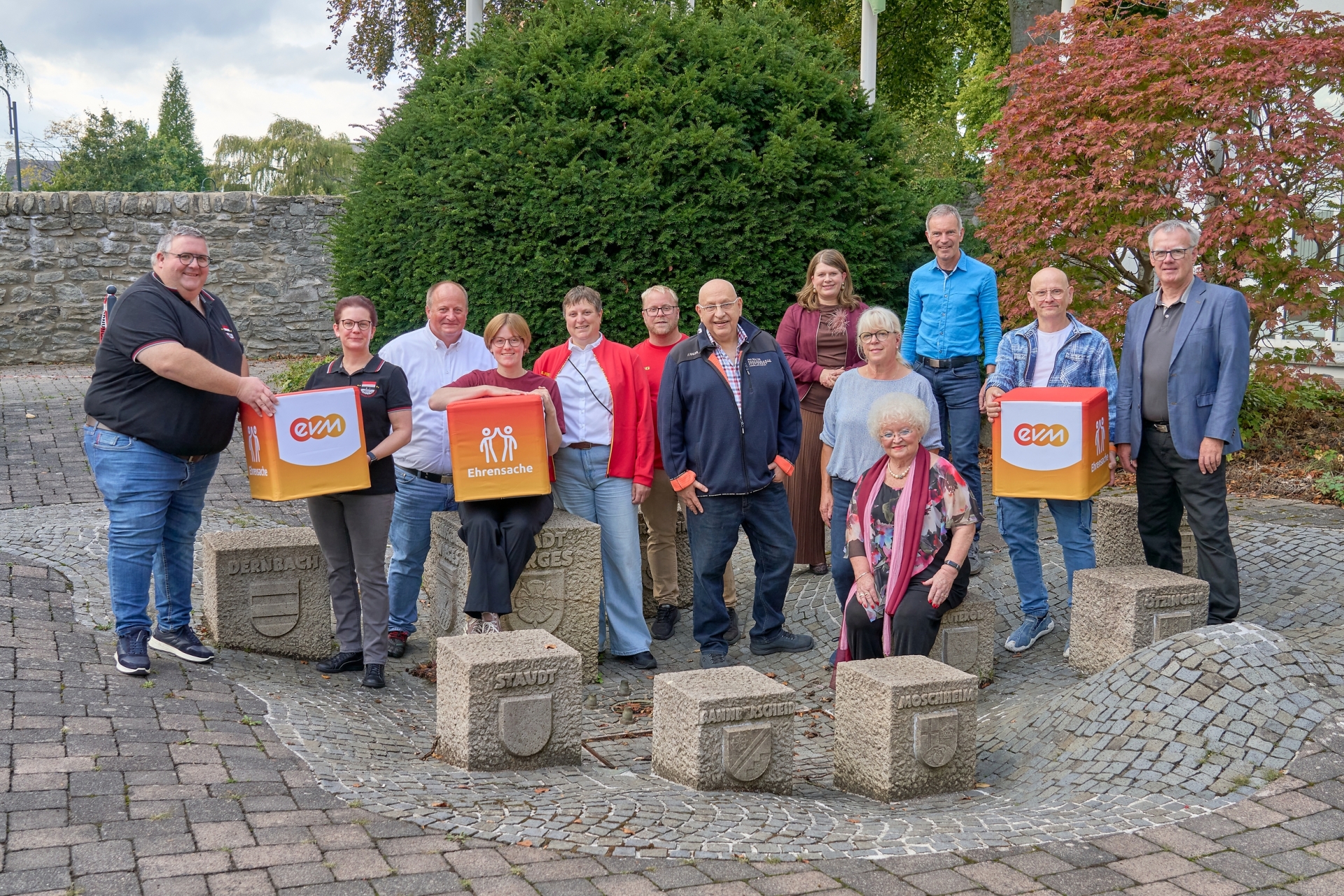 Vertreterinnen und Vertreter des Kulturkreis Mogendorf e.V., der Kirmes Altstars Dernbach e.V. und der DLRG Ortsgruppe Wirges e.V. stehen gemeinsam mit Norbert Rausch von der evm und Bürgermeisterin Alexandra Marzi auf einem Platz im Freien. Mehrere Personen halten „evm‑Ehrensache“-Spendenboxen, die symbolisch für die Förderung der Vereine aus dem Spendenprogramm stehen.