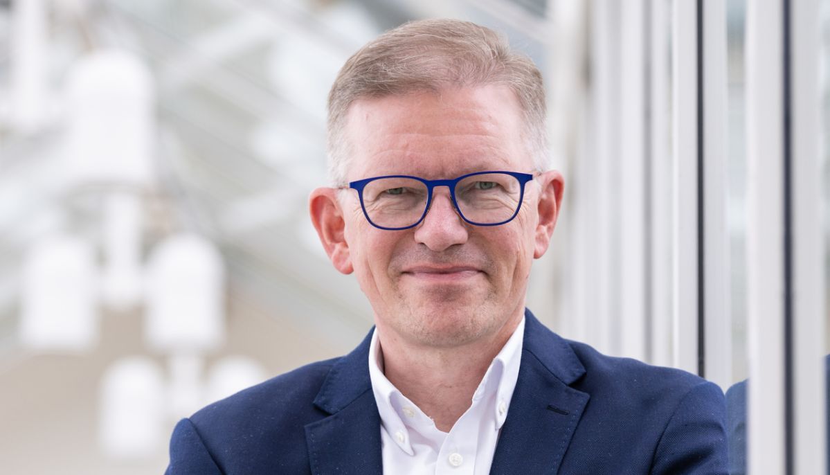 Marcelo Peerenboom steht mit verschränkten Armen in einem hellen, modernen Gebäude vor einer Glasfront. Der Unternehmenssprecher der evm ist Gastgeber des neuen Dialogformats „evm‑Energietreff“, bei dem Bürgerinnen und Bürger Fragen rund um Energie und die evm‑Gruppe stellen können.