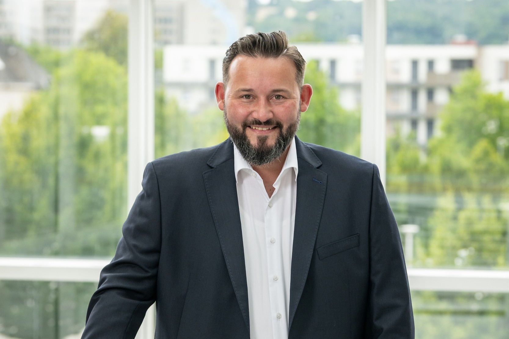 Hendrik Majewski, technischer Geschäftsführer der Energienetze Mittelrhein, steht im Foyer eines modernen Gebäudes an einem Geländer.