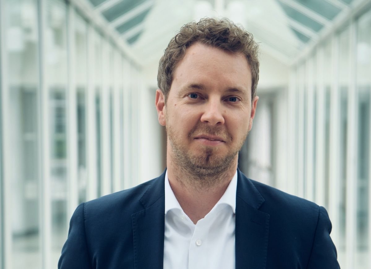 Christoph Hesse Christoph Hesse steht in einem verglasten Verbindungsgang eines modernen Bürogebäudes und blickt in die Kamera. Das Vorstandsmitglied der evm trägt ein dunkles Sakko mit weißem Hemd. Anlass des Porträts ist die Verlängerung seines Vertrags als Mitglied des Vorstands um weitere fünf Jahre.