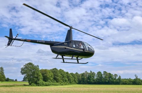 Mit einem schwarzen Helikopter kontrolliert die Crew von Heli Transair im Auftrag der Energienetze Mittelrhein Freileitungen im nördlichen Rheinland‑Pfalz.