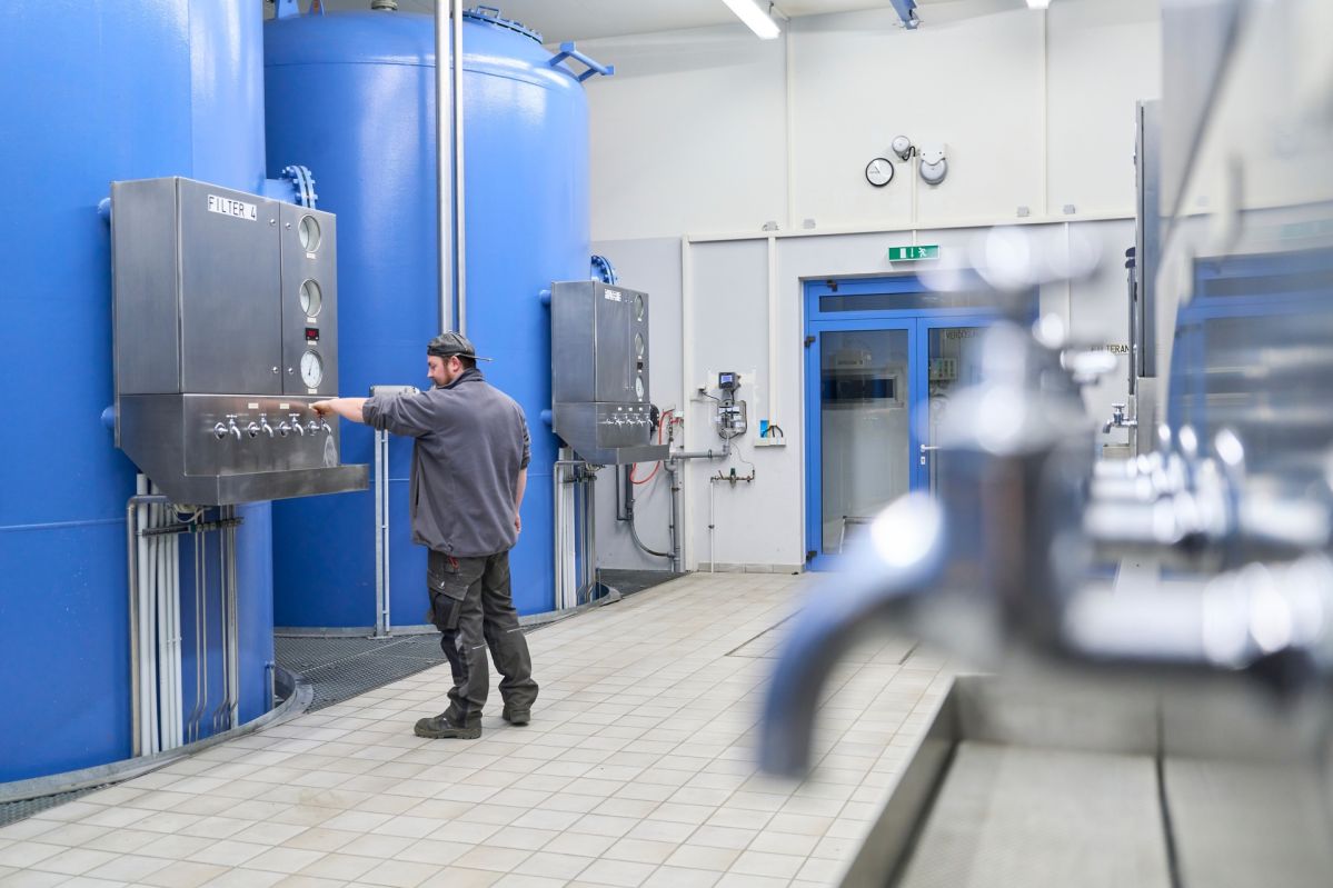 Technischer Raum im Wasserwerk Oberwerth mit großen blauen Behältern und Steueranlagen; eine Person führt Arbeiten an der Anlage aus, die Teil der Maßnahmen zur sicheren Trinkwasserversorgung in Koblenz, Vallendar und Lahnstein sind.