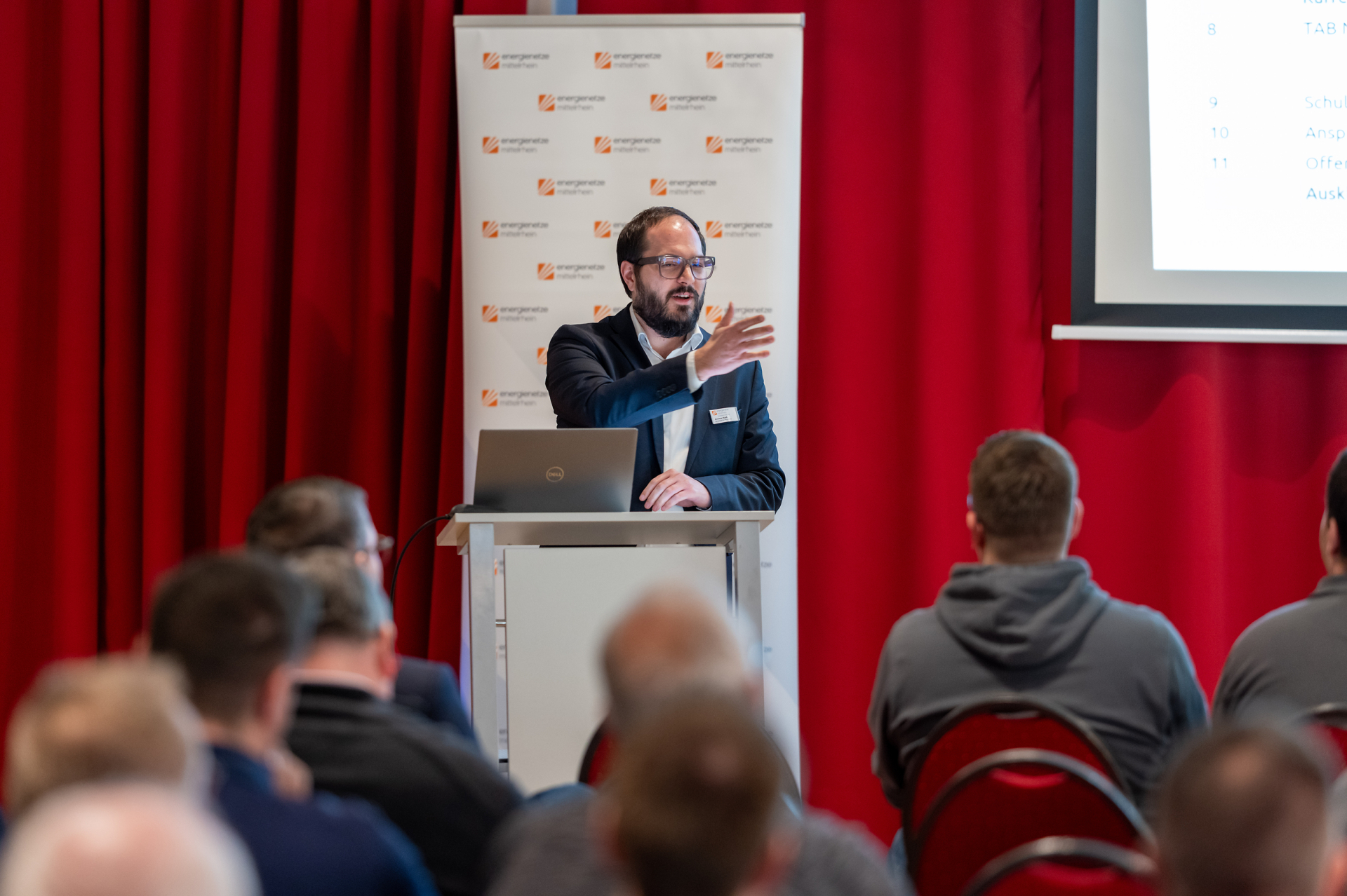 Vortragende Person spricht am Rednerpult zu Teilnehmenden einer enm‑Infoveranstaltung zur Netzübernahme.