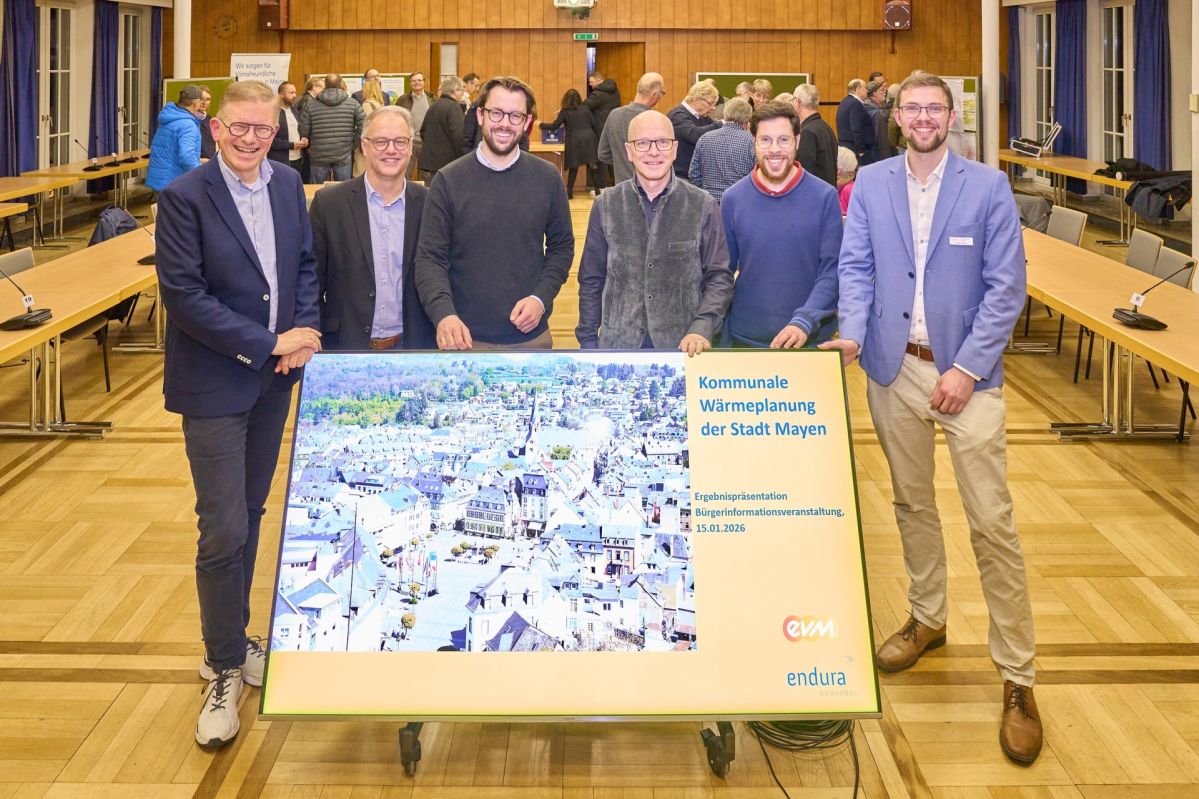 Referenten der Infoveranstaltung zur kommunalen Wärmeplanung der Stadt Mayen stehen vor einer Präsentationstafel im Veranstaltungsraum.