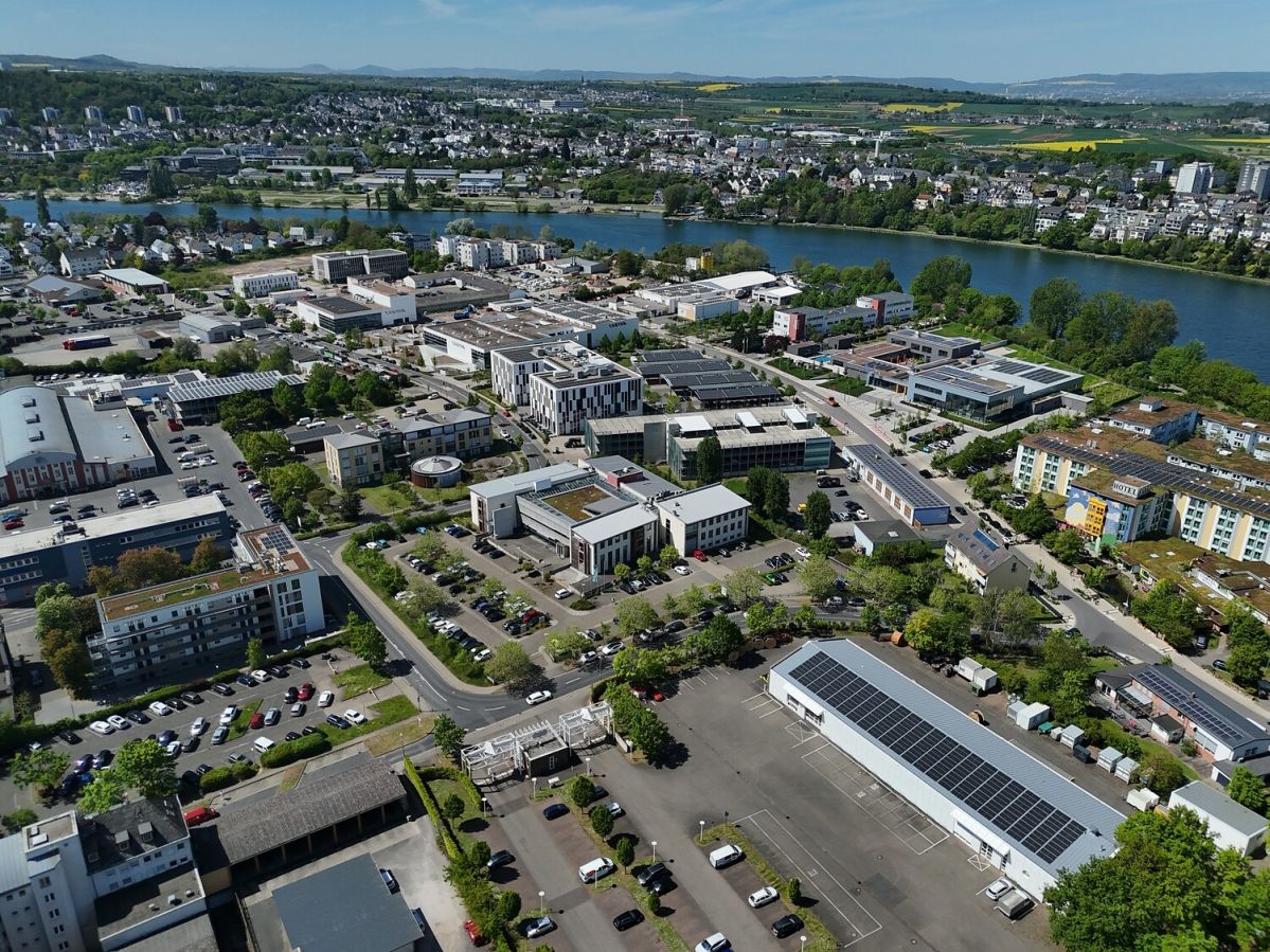 Moselbogen Luftaufnahme eines Gewerbe- und Bürogebiets am Moselbogen in Koblenz-Rauental mit modernen Gebäuden, Straßen und der Mosel im Hintergrund.
