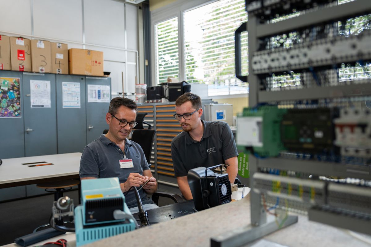 Praktikumstag David Langner David Langner sitzt gemeinsam mit einem Mitarbeiter der Energienetze Mittelrhein in der Ausbildungswerkstatt an einem Arbeitstisch. Vor ihnen befinden sich elektronische Bauteile und eine Übungsanlage für die Elektrotechnik. Während seines Praktikumstags erhielt der Oberbürgermeister Einblicke in die Ausbildung und technische Arbeitsbereiche der evm-Gruppe.