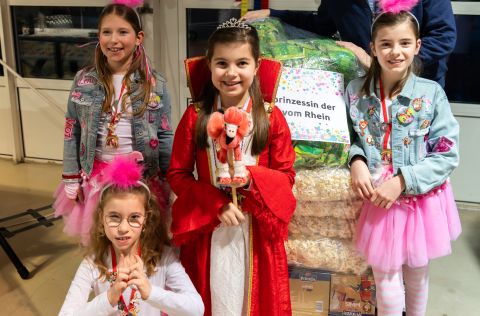 Palettenparty Kinderprinzessin der Perlen vom Rhein und ihr Gefolge stehen vor einer Palette Wurfmaterial in festlicher Karnevalsdekoration.