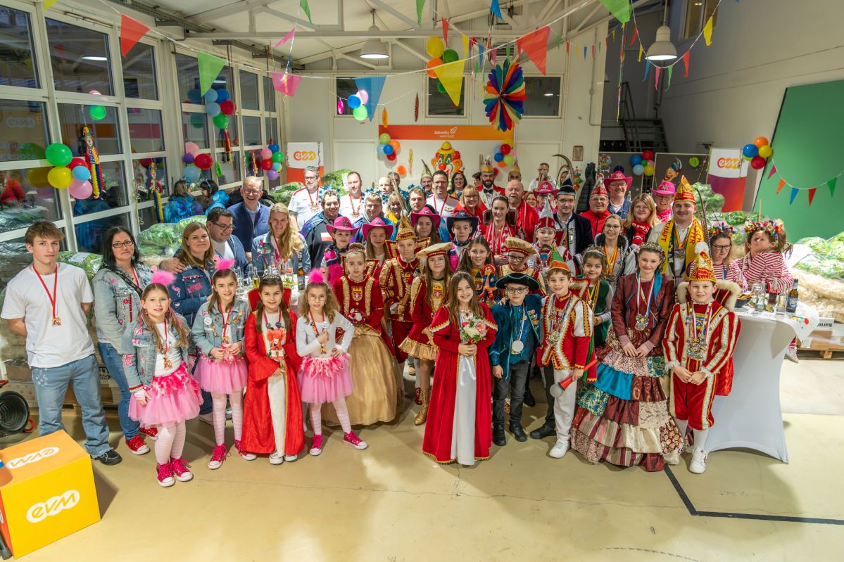 Palettenparty Große Gruppe der elf Gewinnervereine der evm‑Palettenparty posiert in einer bunt geschmückten Halle bei der Übergabe der Paletten voller Wurfmaterial.