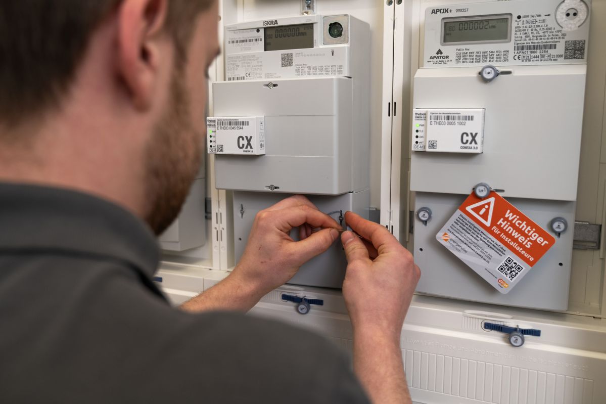 Smart-Meter-21 Eine Person installiert ein intelligentes Messsystem (Smart Meter) in einem Zählerschrank. Auf dem Bild sind digitale Stromzähler und die zugehörige Kommunikationstechnik zu sehen. Smart Meter ermöglichen die digitale Erfassung von Verbrauchsdaten und bilden eine wichtige Grundlage für die Digitalisierung der Energiewende.