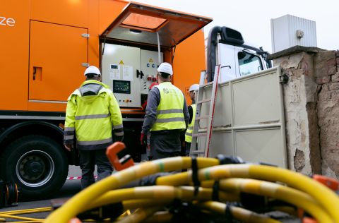 Wartung Mehrere Mitarbeitende der Energienetze Mittelrhein bedienen das mobile Stromaggregat während eines Netzeinsatzes. Im Vordergrund liegen Anschlusskabel, während die Techniker die Steuerung des Fahrzeugs überwachen. Das Aggregat unterstützt die Stromversorgung bei Wartungsarbeiten und Netzstörungen.