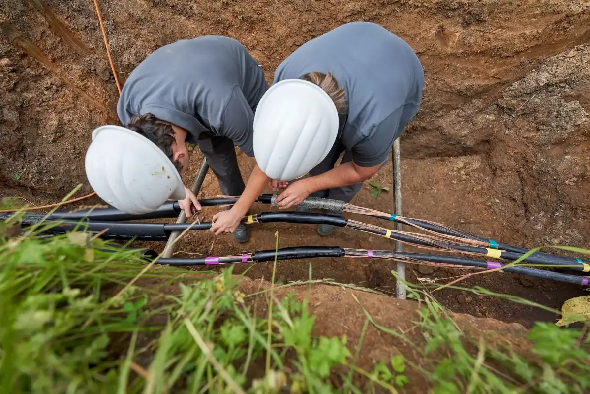 Zwei Männer im Graben arbeiten an den Leitungen
