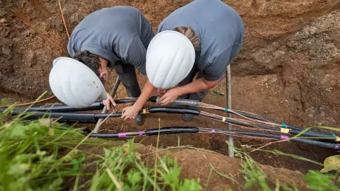 Zwei Männer im Graben arbeiten an den Leitungen