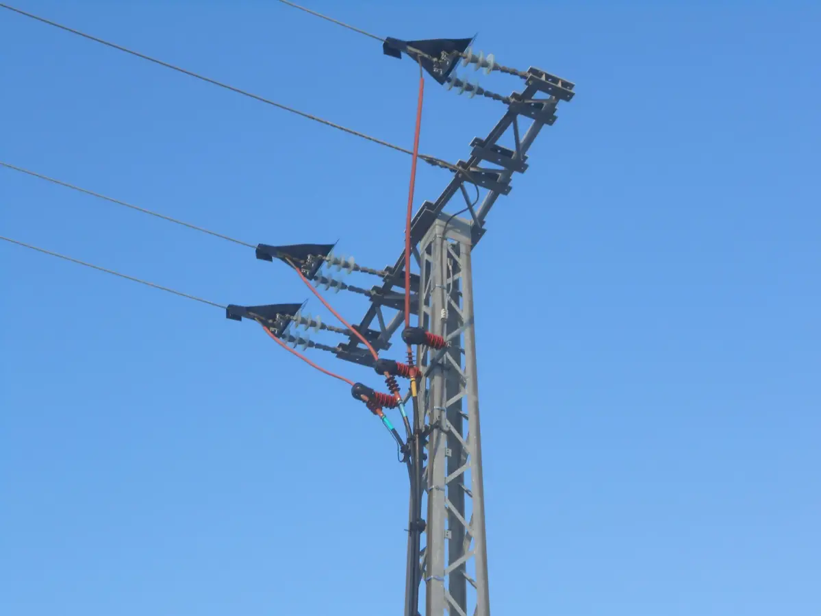 Ein Strommast von unten fotografiert vor einem blauen Himmel.