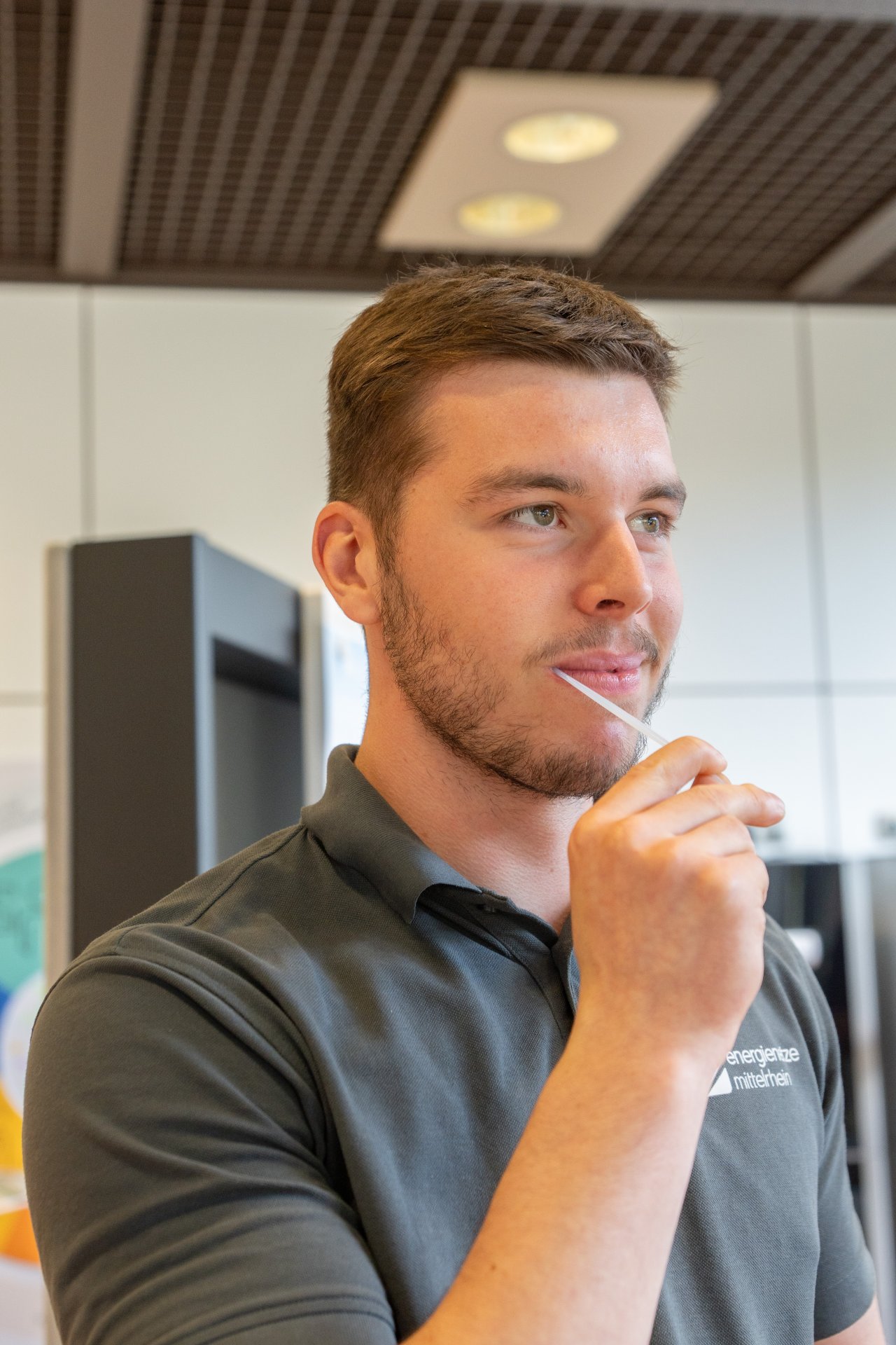 DKMS-1 Ein Mann mit einem grauen enm Poloshirt hat ein schmales weißes Stäbchen im Mund.