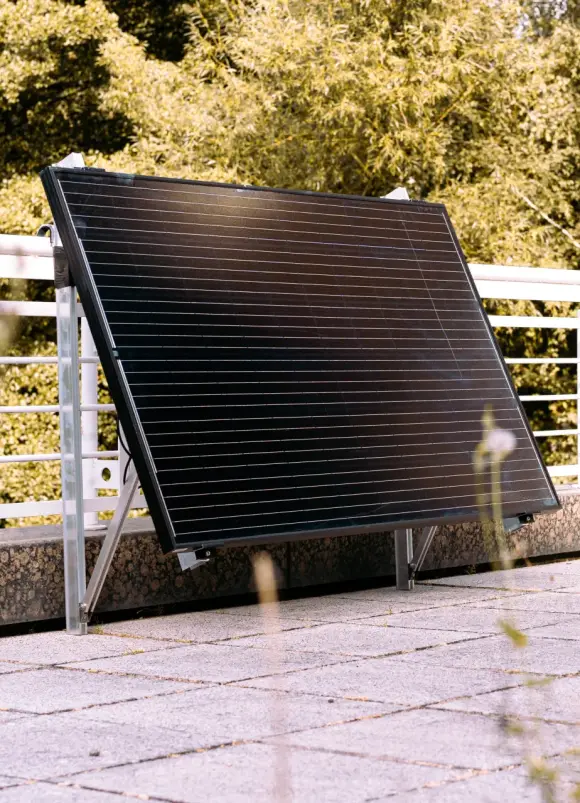 Ein Solarpanel ist an einem Balkongelände montiert.