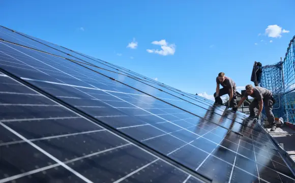 evm Handwerker montieren eine Solaranlage auf ein Dach.