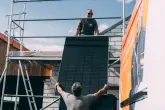 Handwerker reichen Solarpanel aufs Dach