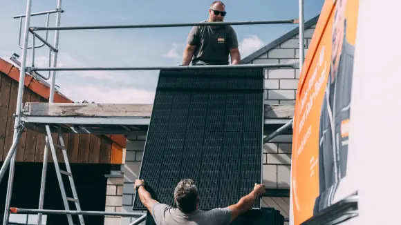 Handwerker reichen Solarpanel aufs Dach