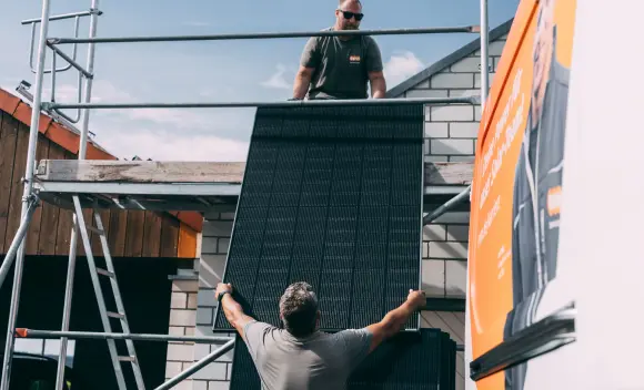 Handwerker reichen Solarpanel aufs Dach