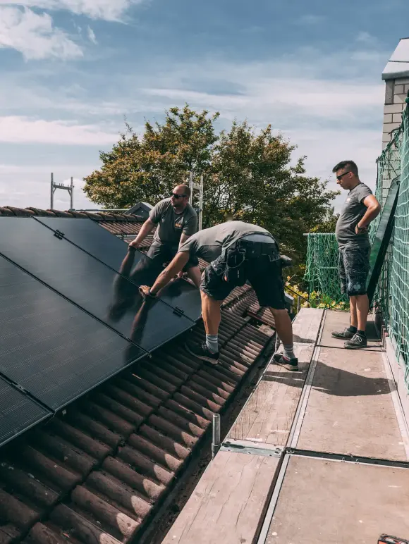 evm Handwerker montieren eine Solaranlage auf ein Dach.