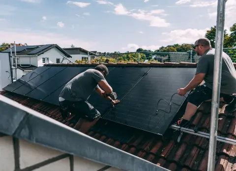 evm Handwerker montieren eine Solaranlage auf ein Dach.