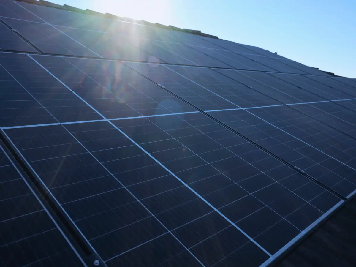 Eine Nahaufnahme einer PV-Anlage in der sich die Sonne spiegelt.