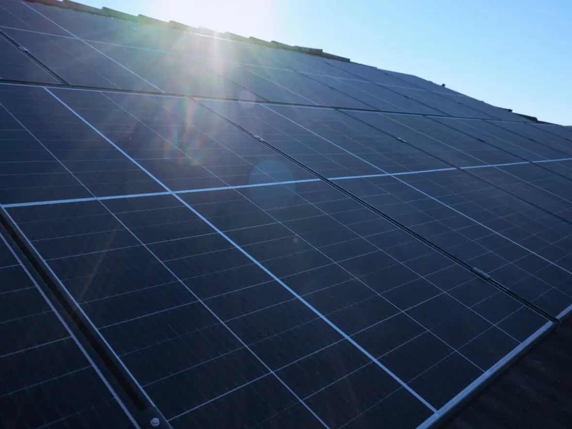 Eine Nahaufnahme einer PV-Anlage in der sich die Sonne spiegelt.